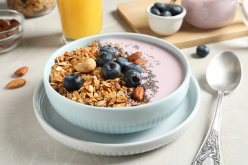 Bowl of tasty oatmeal with blueberries and yogurt on light grey marble table