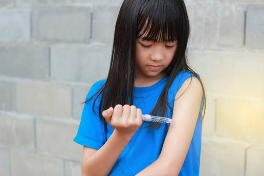 An Asian girl using insulin pen.Self insulin injection.Diabetes in children.