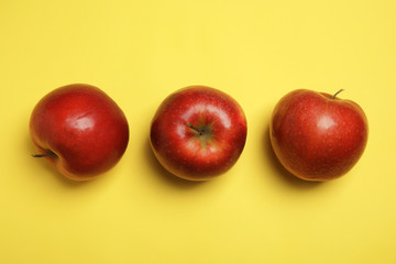 Flat lay composition with ripe juicy red apples on yellow background