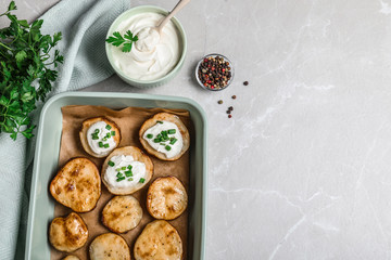 Sour cream dressing and delicious potato wedges on light grey table, flat lay