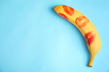 Top view of fresh banana with red lipstick marks on blue background, space for text. Oral sex concept - obrazy, fototapety, plakaty