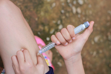 An Asian girl using insulin pen.Self insulin injection.Diabetes in children.