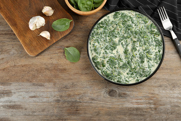 Tasty spinach dip on wooden table, flat lay