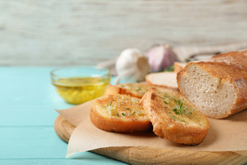 Slices of toasted bread with garlic and herbs on light blue wooden table