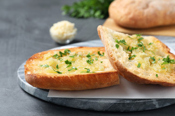 Slices of delicious toasted bread with garlic and herbs on grey table, closeup