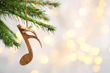 Tuinposter Fir tree branch with wooden note against blurred lights, space for text. Christmas music © New Africa