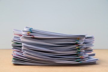 Stack of document paper with colorful paperclip place on wooden table.