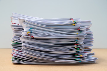 Stack of document paper with colorful paperclip place on wooden table.