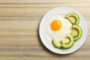 Delicious breakfast with fried egg served on wooden table, top view. Space for text