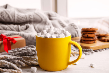Cup of hot cocoa with marshmallows on window sill. Winter drink