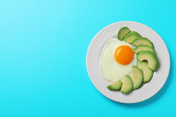 Plate of fried egg and avocado on light blue background, top view with space for text. Healthy breakfast