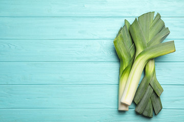 Fresh raw leeks on blue wooden table, flat lay with space for text. Ripe onion