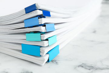 Stack of documents with binder clips on marble table, closeup