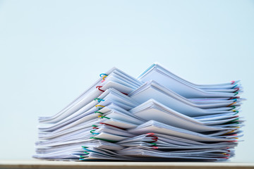 Stack of document paper with colorful paperclip place on wooden table with copy space.