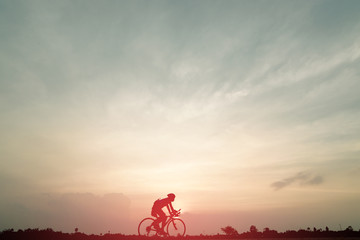 Silhouette of cyclist ride bicycle on sunset background. A man Ride on bike on the road with...