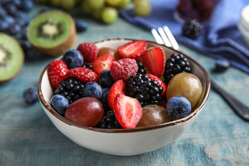 Fresh tasty fruit salad on blue wooden table, closeup