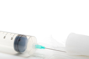 A medical syringe with a needle and bandage lie on a table in a hospital isolated on white background.