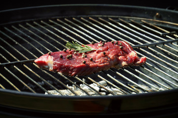 Tasty steak with pepper and rosemary on barbecue grill