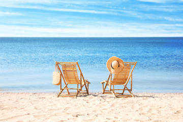 Wooden deck chairs on sandy beach near sea
