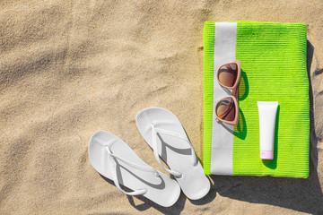 Flat lay composition with different beach accessories on sand. Space for text