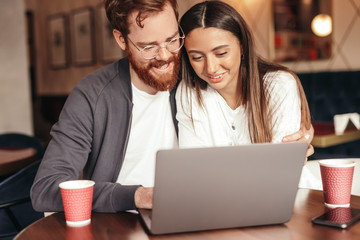 Young couple browsing laptop in cafe