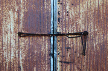 錆びた鉄の棒で施錠している古い鉄の扉