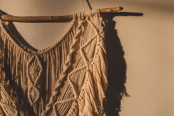 Detailed shot of the macrame wall hanging. DIY boho wall tapestry hanging on the wall in the morning sun