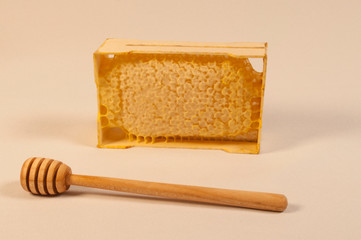 Frame with sealed honeycomb honey and a wooden spoon for mixing and tasting natural honey
