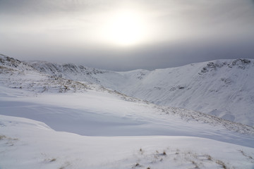 The snow covered summits of High Street and Thornthwaite Crag from Rampsgill Head near Hartsop in the Lake District.