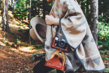Fototapeta na wymiar Young girl in a hat and with a vintage camera in the autumn forest