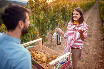 Fototapeta premium Man and woman on autumn vineyard tasting wine.