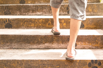 Young man walking up the stairs. A man is climbing on cement step.