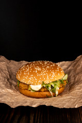 Chicken burger bun with sesame seeds, chicken and sauce, vertical