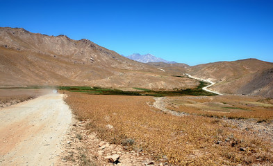 Scenery between Kabul and Bamyan (Bamiyan) in Afghanistan. Taken from the road on the southern route between Kabul and Bamyan (Bamiyan) in central Afghanistan. Dusty road through mountain scenery.