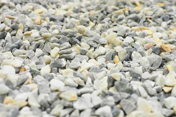 Selective focus of a lot of tiny pieces of gravel on the road in grey tone with rough surface and texture used for construction and also for background and decoration. 