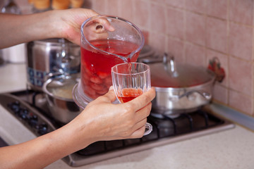 homemade cold sugared strawberry juice in the kitchen filling up the glass