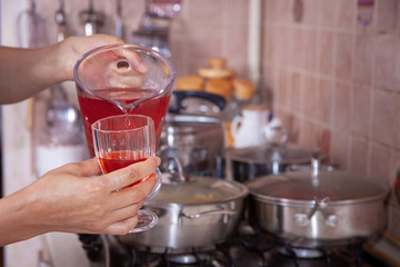 homemade cold sugared strawberry juice in the kitchen filling up the glass