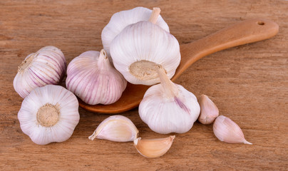garlic in a wooden spoon on a wooden floor
