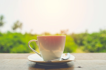 Hot coffee on table with fresh garden background