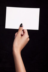 hand holding white card on black background - copyspace