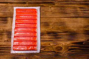 Vacuum pack of crab sticks on a wooden table. Top view