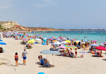 People enjoy summer holidays on the sandy beach Campoamor, Province Alicante, Spain