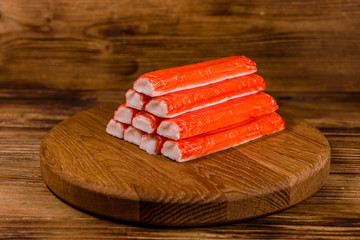 Cutting board with pile of crab sticks on a wooden table