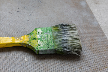 Dirty green paintbrush on a chipboard. House renovation