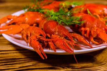 Plate with boiled crayfishes on wooden table