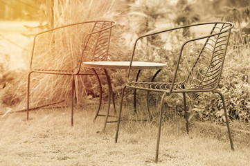 Fototapeta na wymiar Empty relax table and chair in house garden. vintage filter