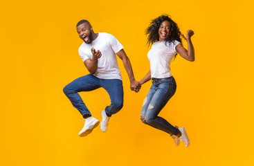 Joyful african couple having fun over yellow background