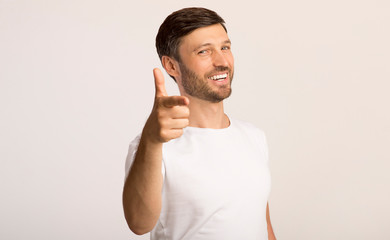 Guy pointing finger at camera standing on white background