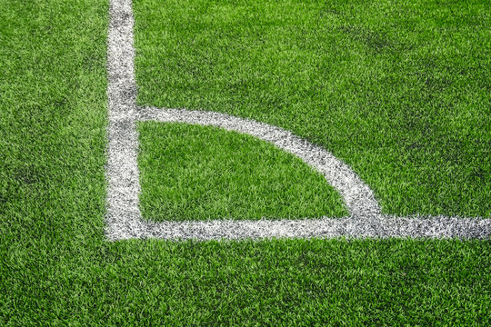 Marking white paint of a corner on a green lawn of the football field.