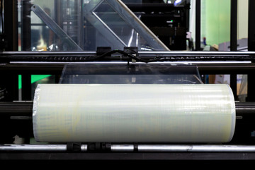 roll of plastic packaging film on the automatic packing machine in food product factory. industrial...